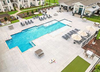 A large swimming pool surrounded by lounge chairs and umbrellas.